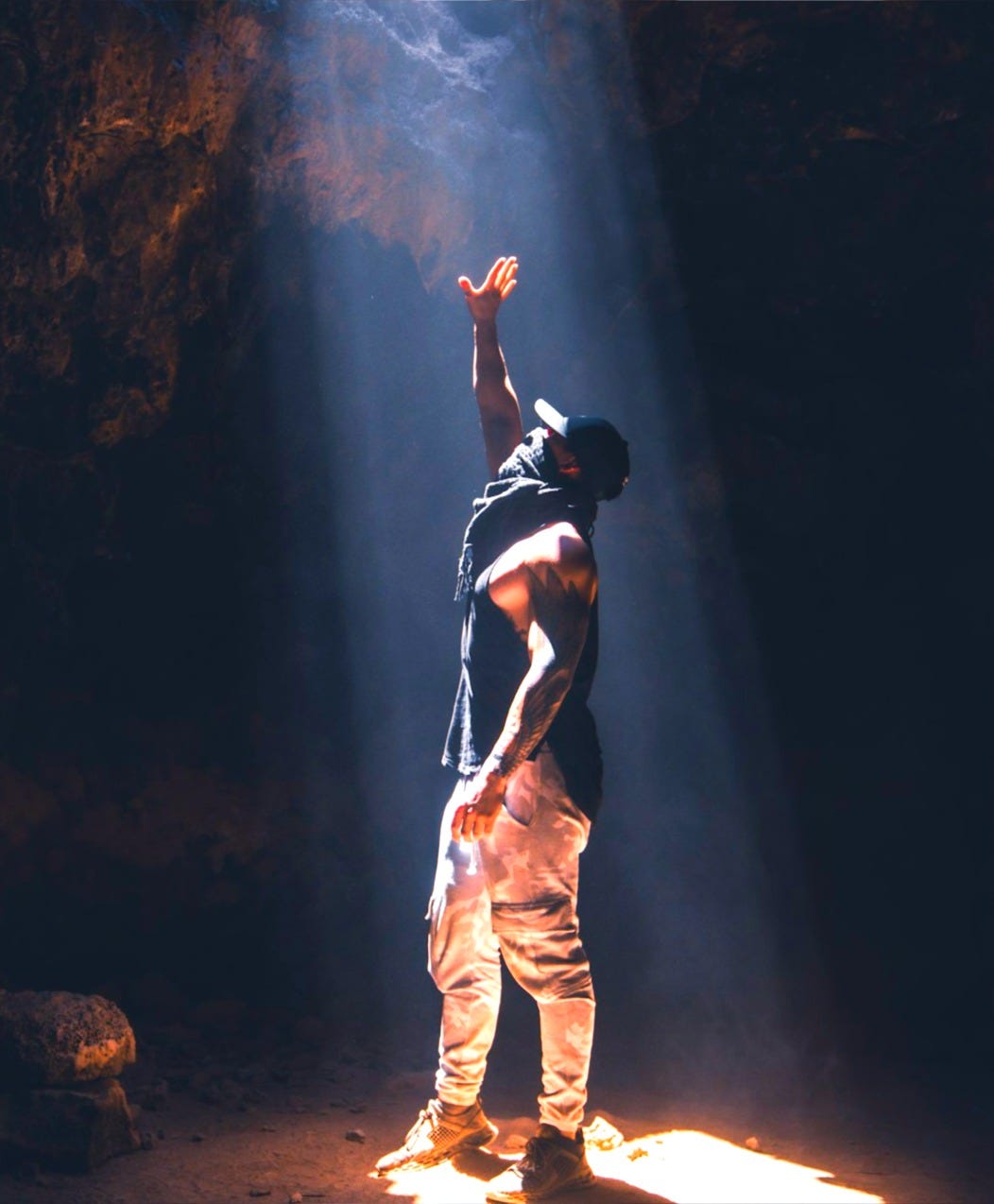 man in black tank top and beige pants standing on rock