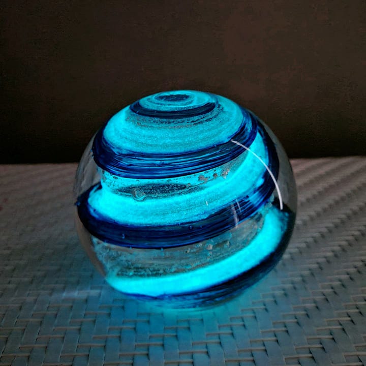 Glass orb containing cremains and blue ribbons