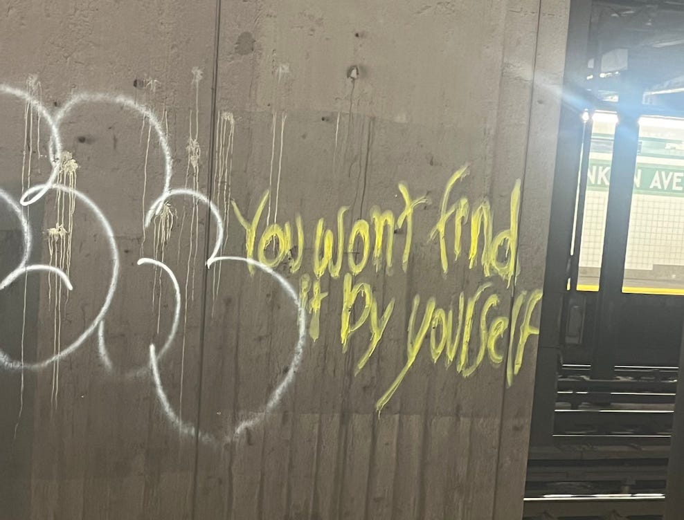 graffiti in a New York subway train station. it reads "you won't find it by yourself"