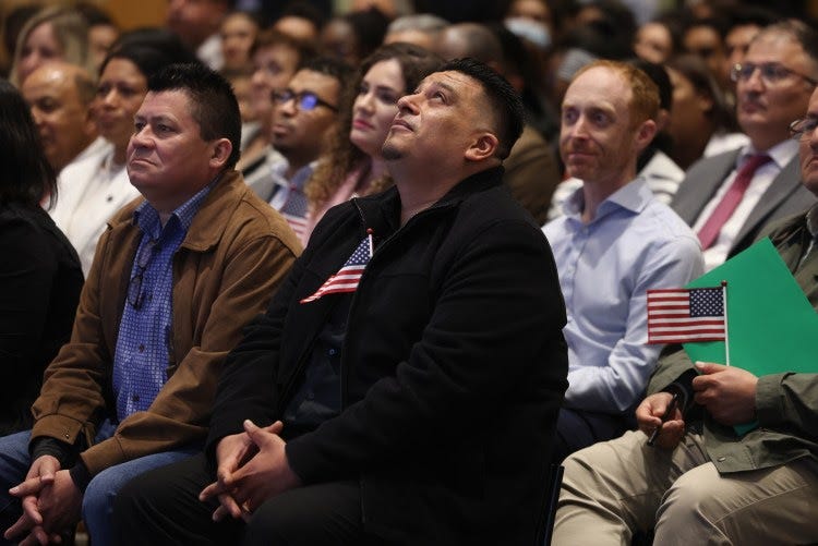 People react after getting their certificate of naturalization during a naturalization ceremony.