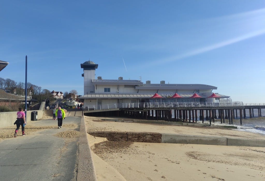 A building with a small tower on the pier, with sandy beaches in front.