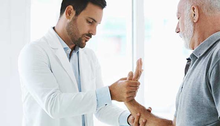 Doctor looking at man's hand.