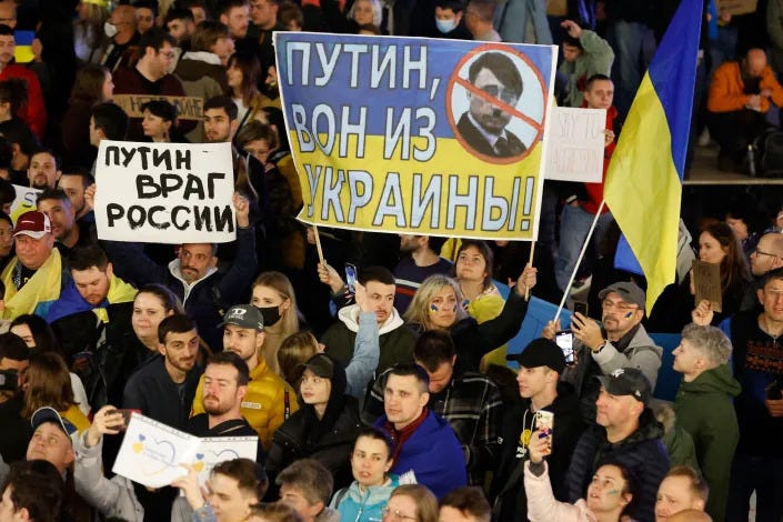 Demonstrators hold up a sign showing the Ukrainian flag with text reading in Russian Demonstrators hold up a sign showing the Ukrainian flag with text reading in Russian