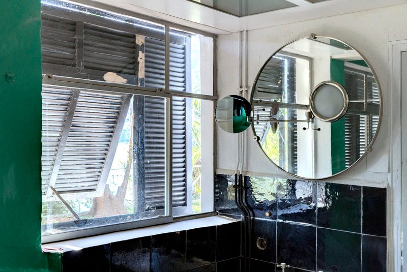 A round mirror next to windows