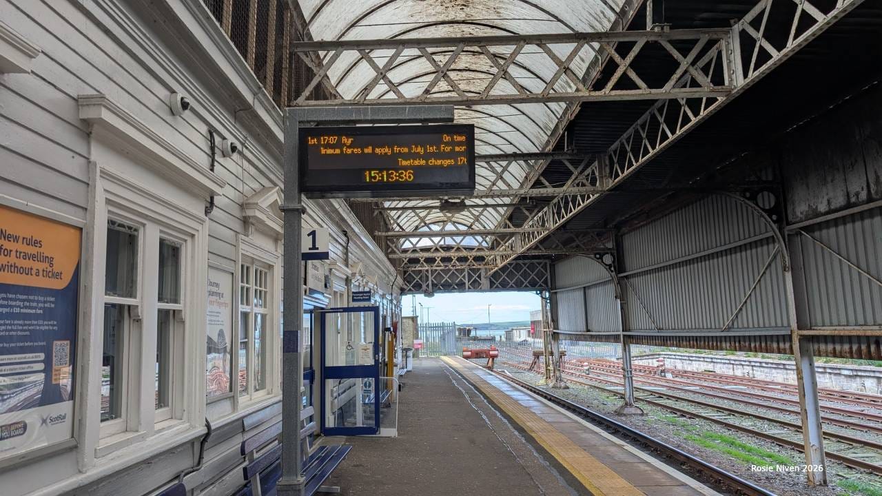 An empty station platform with a train to Ayr on the board An empty station platform with a train to Ayr on the board