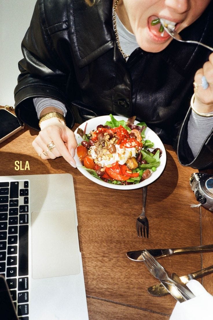 Close-up of a woman eating a colorful salad with a fork, wearing a leather jacket and layered gold jewelry Close-up of a woman eating a colorful salad with a fork, wearing a leather jacket and layered gold jewelry