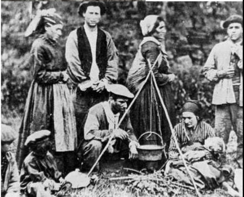 Vintage photo of peasant family cooking outdoors over fire.