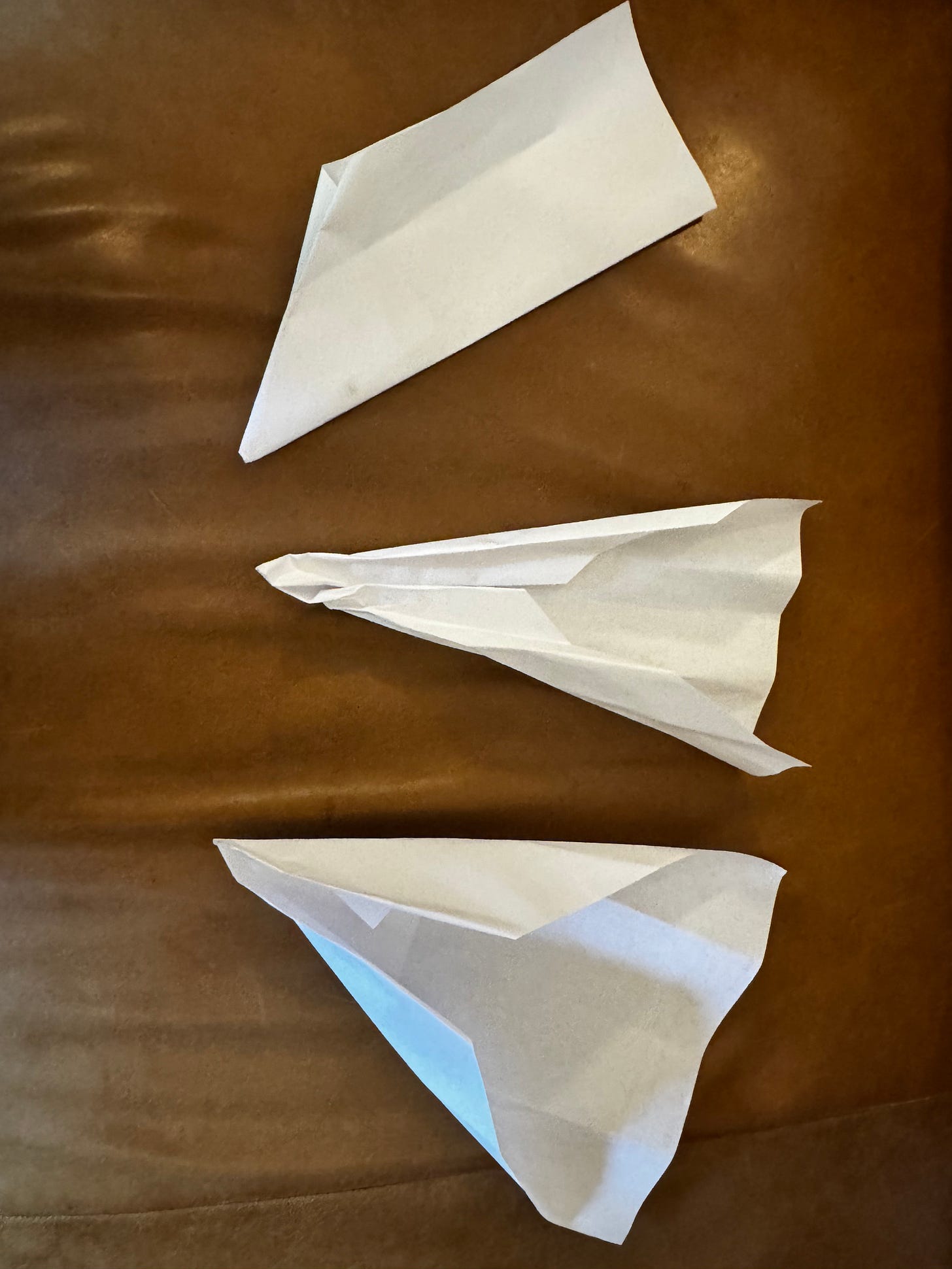 Three crumpled paper airplanes made by a small child, showing simple folding and playful creativity.