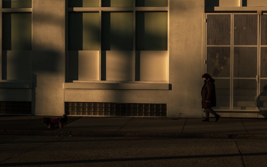 person in black jacket walking on sidewalk during daytime person in black jacket walking on sidewalk during daytime