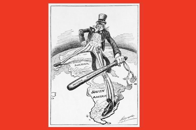 A black and white political cartoon shows an extra tall and lanky Uncle Sam with one foot in Alaska and one in South America as he straddles the Americas and holds a big "Monroe Doctrine" stick.
