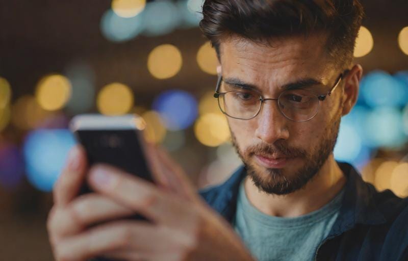A man looking at a smartphone with a neutral expression