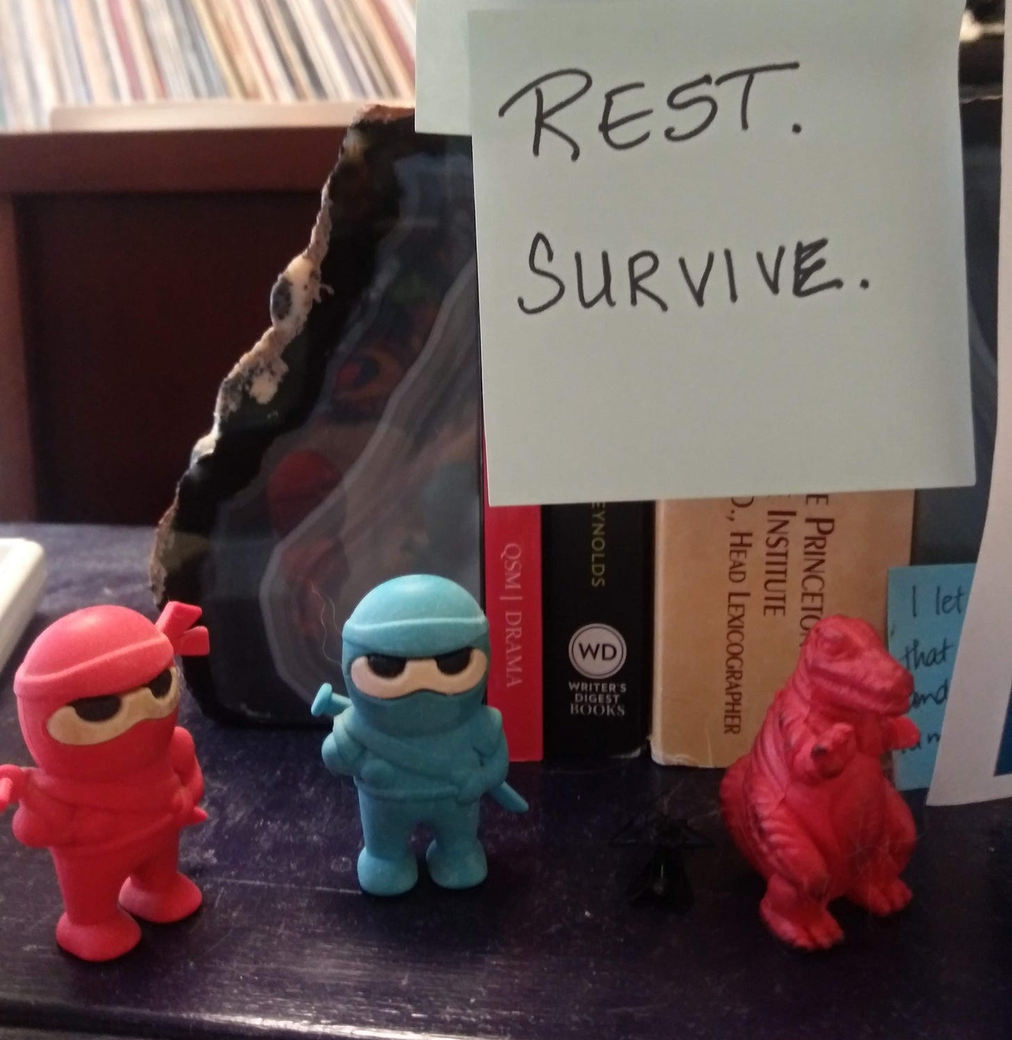 desk with post in note reading rest. survive.