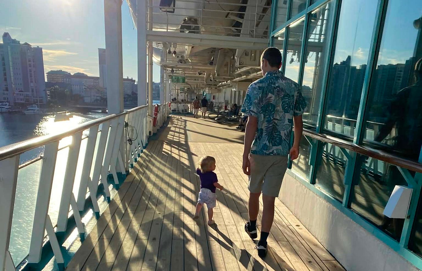a baby and her dad walk down the promenade deck on a cruise ship