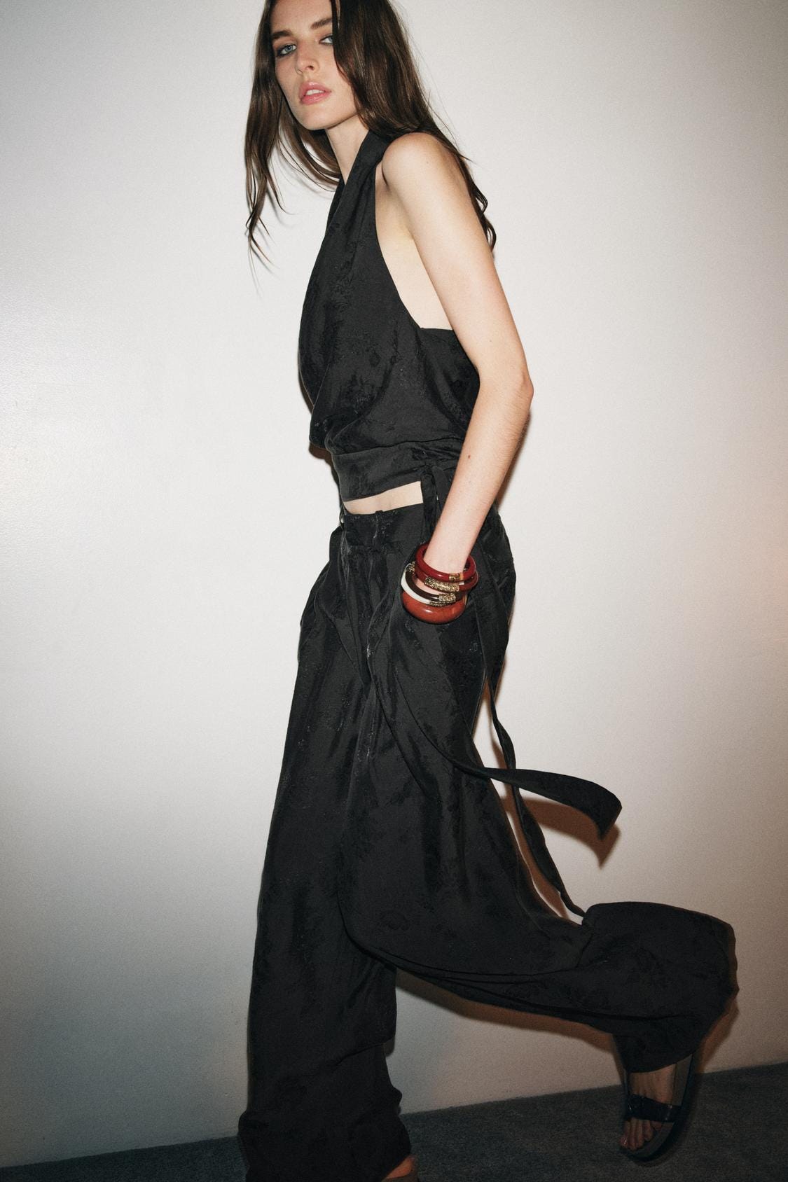 Black halter neck top and wide-leg trousers set with open back, floral jacquard fabric detail.