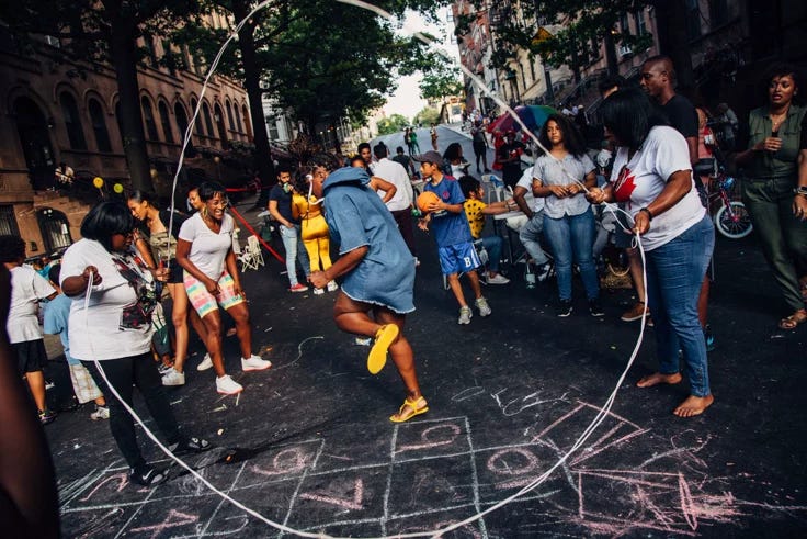 This may contain: a group of people standing around in the middle of a street with chalk writing on it