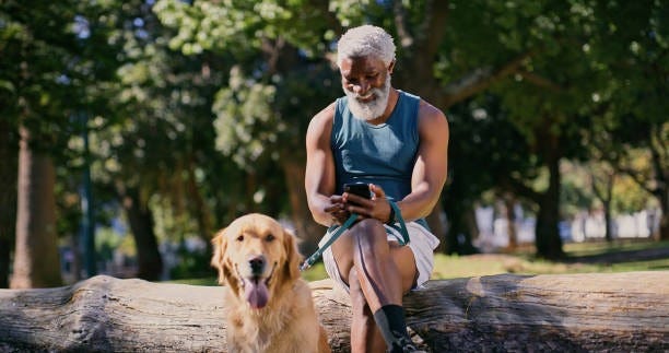 Man walking dog checking his phone.