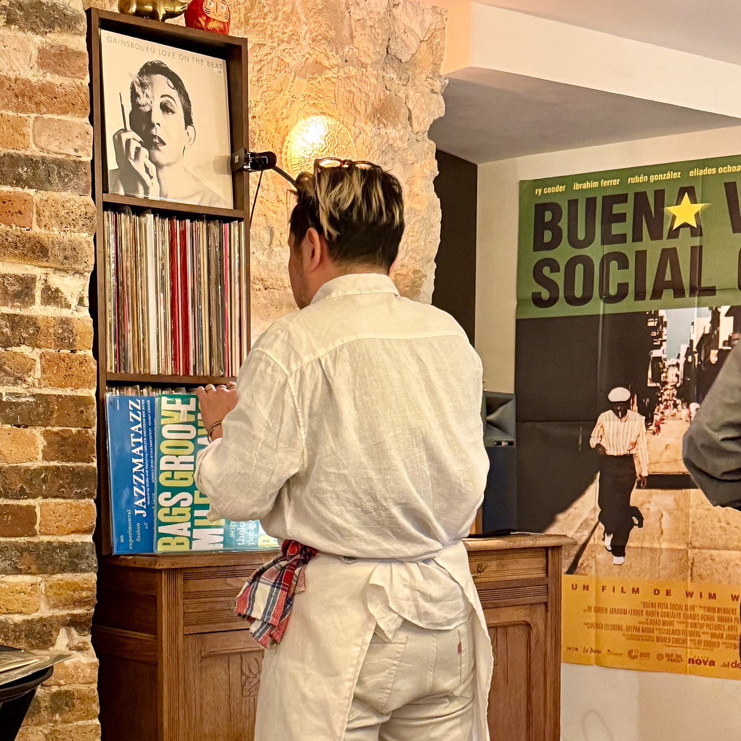 Turntable and record collection against exposed stone wall at Masaikuta, Paris 11th