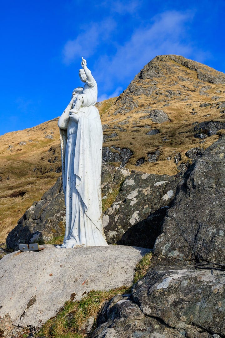 Madonna and Child statue on the shoulder of Heabhal on Barra and the view to Castlebay from it © Felicity Martin