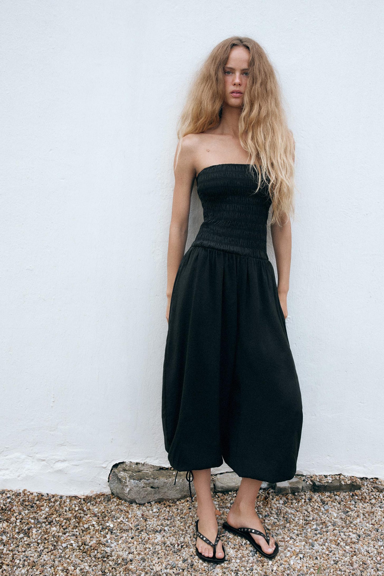 Black strapless top set with a gathered bodice, wide-leg pants with a gathered hem, and black studded sandals. Black strapless top set with a gathered bodice, wide-leg pants with a gathered hem, and black studded sandals.