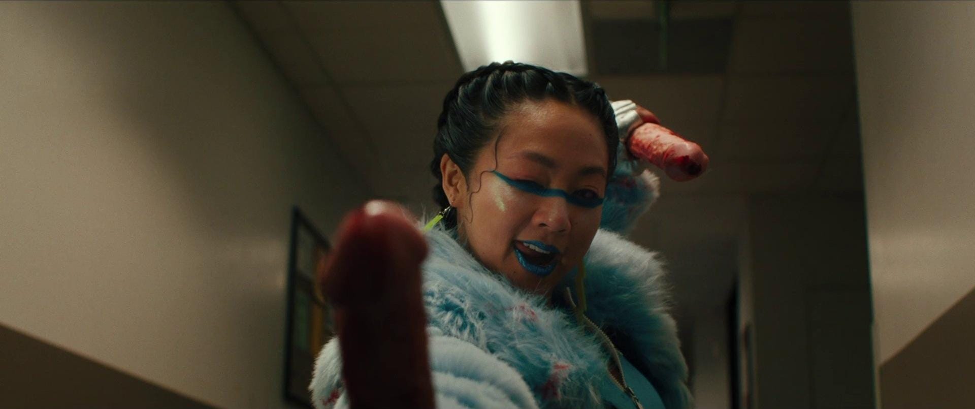 Screenshot from "Everything Everywhere All At Once." Jobu, wielding dildo nunchucks, winks to the camera (and her mother).