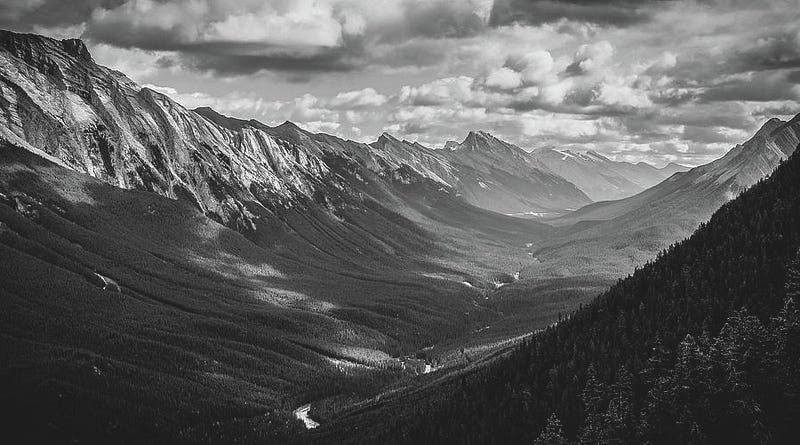 Sweeping black and white view of Bow Valley with layered mountain ridges, deep shadows, and dramatic sky.
