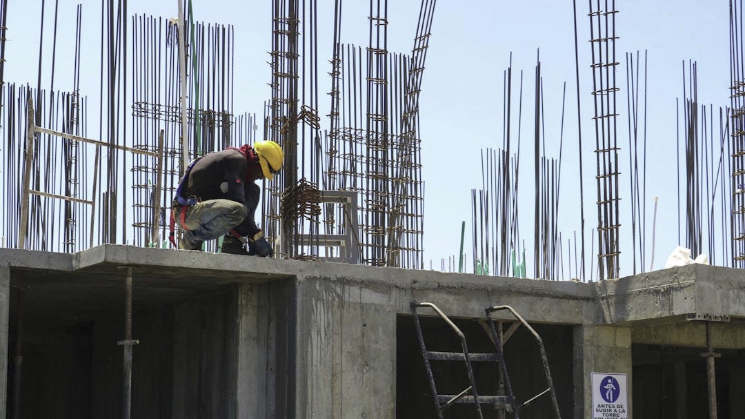 man kneeling on unfinished building during daytime