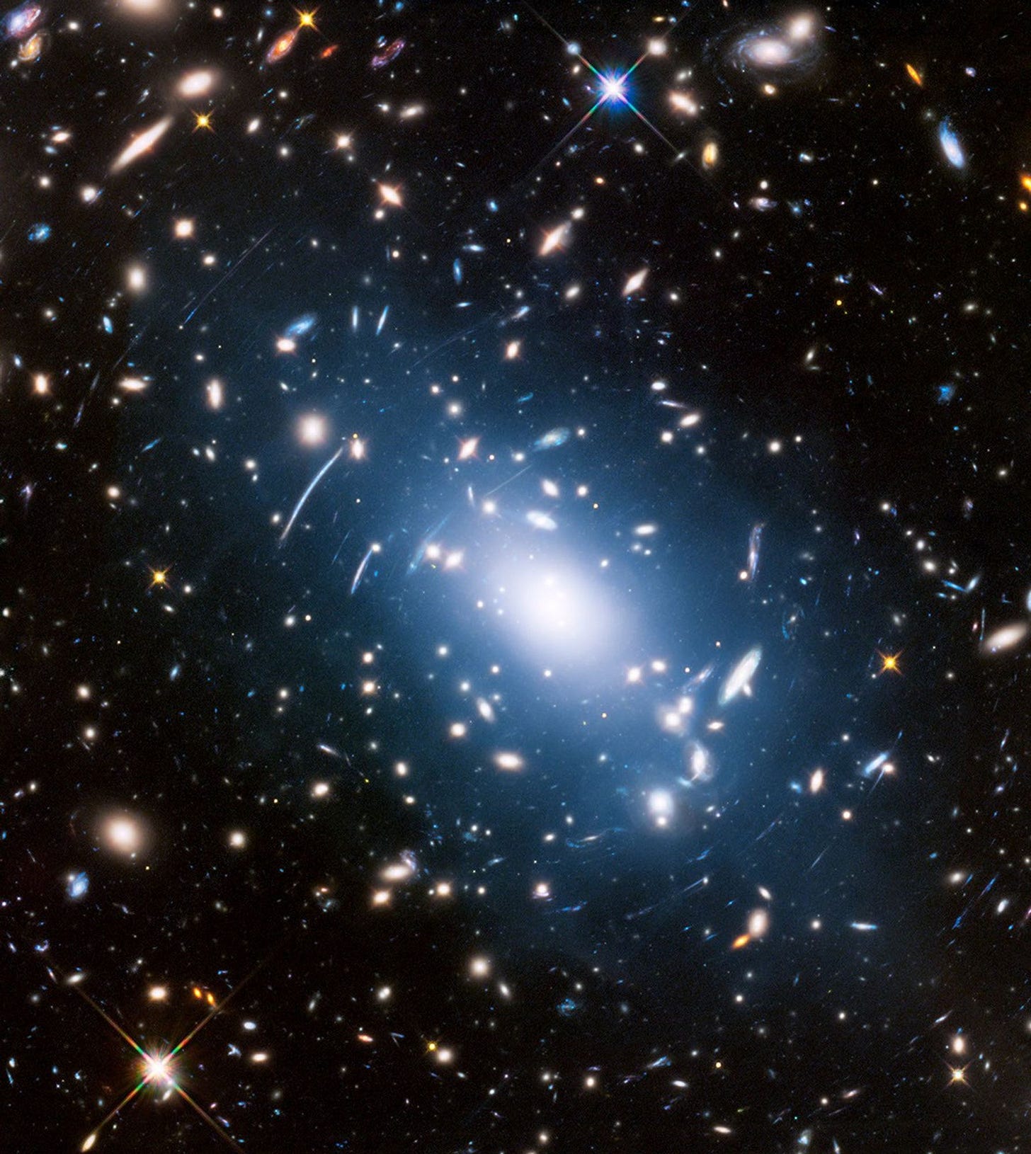 A bright galactic cluster with numerous galaxies, including fascinating jellyfish galaxies and stars, is surrounded by a blue glow and light distortions against a dark background. A bright galactic cluster with numerous galaxies, including fascinating jellyfish galaxies and stars, is surrounded by a blue glow and light distortions against a dark background.