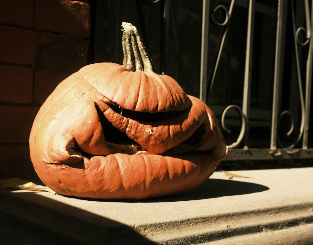 A pumpkin sitting on a ledge outside of a building