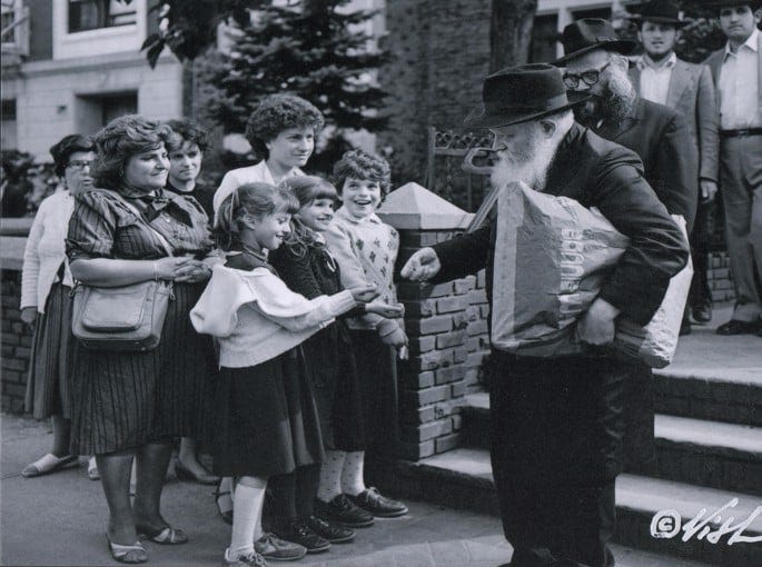 A Leningrad-trained photographer, Shlomo Vishinsky arrived in Crown Heights in the early 1980s and began focusing his camera on the Rebbe and his court. Here the Rebbe distributes coins to be given to charity to young children. - Shlomo Vishinsky | Courtesy Zev Markowitz / Chai Art Gallery A Leningrad-trained photographer, Shlomo Vishinsky arrived in Crown Heights in the early 1980s and began focusing his camera on the Rebbe and his court. Here the Rebbe distributes coins to be given to charity to young children. - Shlomo Vishinsky | Courtesy Zev Markowitz / Chai Art Gallery