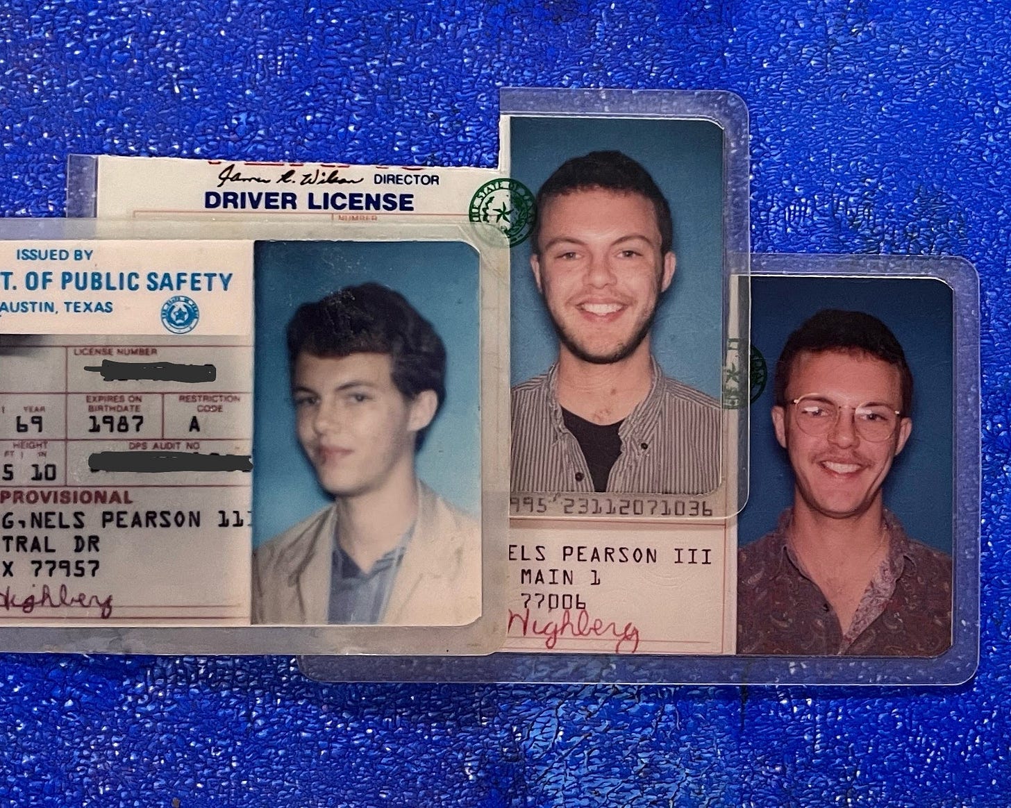 Three old Texas driver's licenses arranged side by side on a vivid blue textured background. Each ID features a portrait of the same person at different young adult stages, showing changes in hairstyle, expression, and clothing style over time. Three old Texas driver's licenses arranged side by side on a vivid blue textured background. Each ID features a portrait of the same person at different young adult stages, showing changes in hairstyle, expression, and clothing style over time.