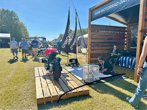 an artist doing a large live sketch of a concept bike; the race track; vintage bikes, and a cigar