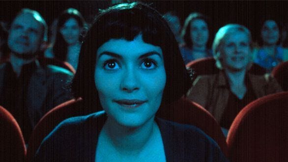 This may contain: a woman with dark hair and blue eyes sitting in front of an audience