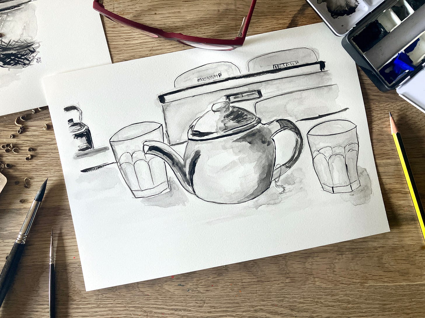 Painting of teapot and two glasses on a kitchen table sits atop a table surrounded by art materials