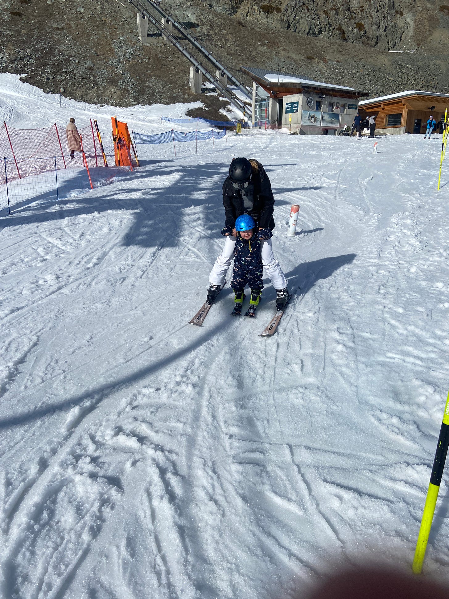 Toddler skiing in-between moms legs