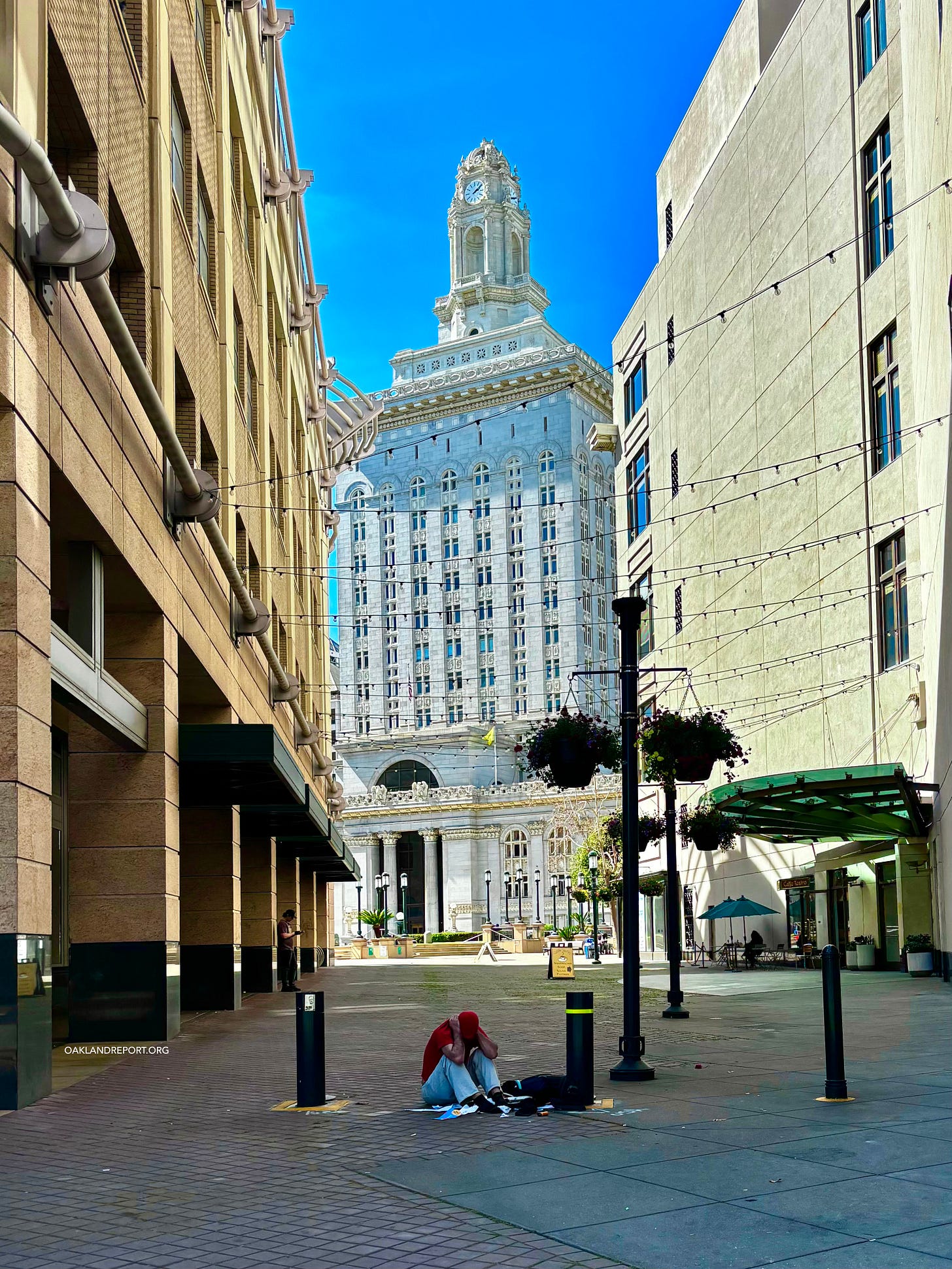 A man sits on the pavement outside Oakland City Hall on Mar. 16, 2026. (Image source: Oakland Report) A man sits on the pavement outside Oakland City Hall on Mar. 16, 2026. (Image source: Oakland Report)