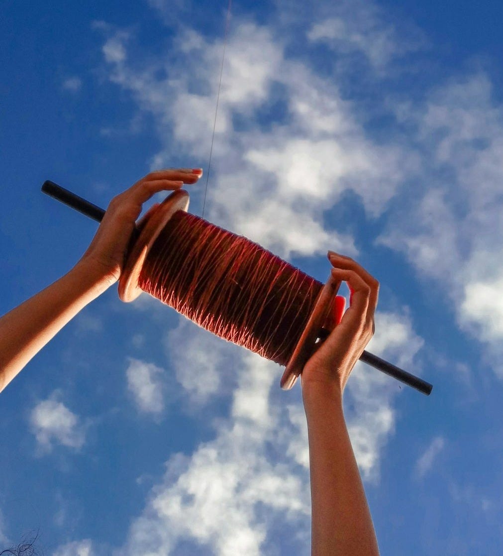low-angle photo of kite thread spool under cloudy sky
