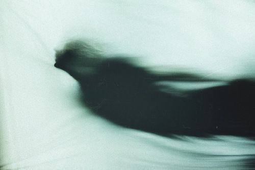 This may contain: blurry photograph of a person on a bed with the sheets pulled back in front of them