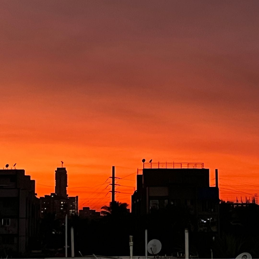 An orange sky with a silhouette of a city skyline, being used as a feature image for an article on find your voice as a writer and artist