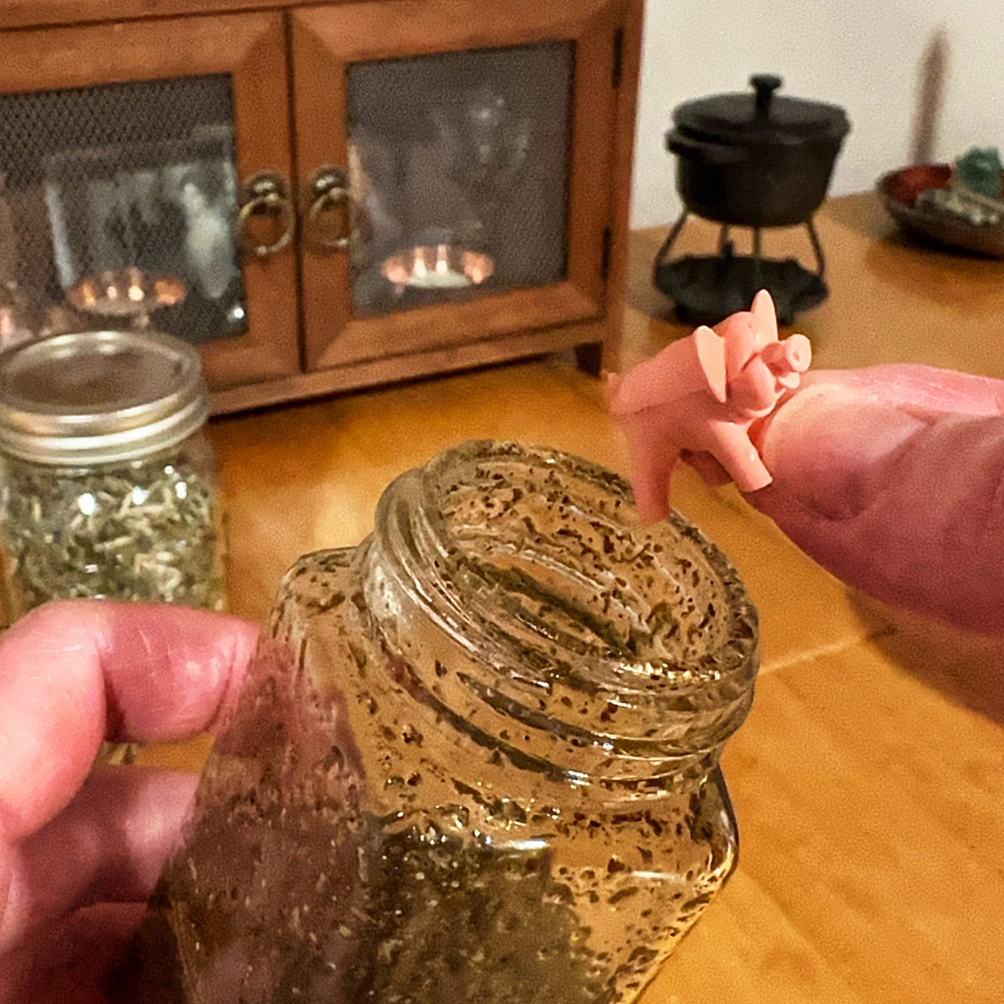 a hand places a tiny toy pig in a jar