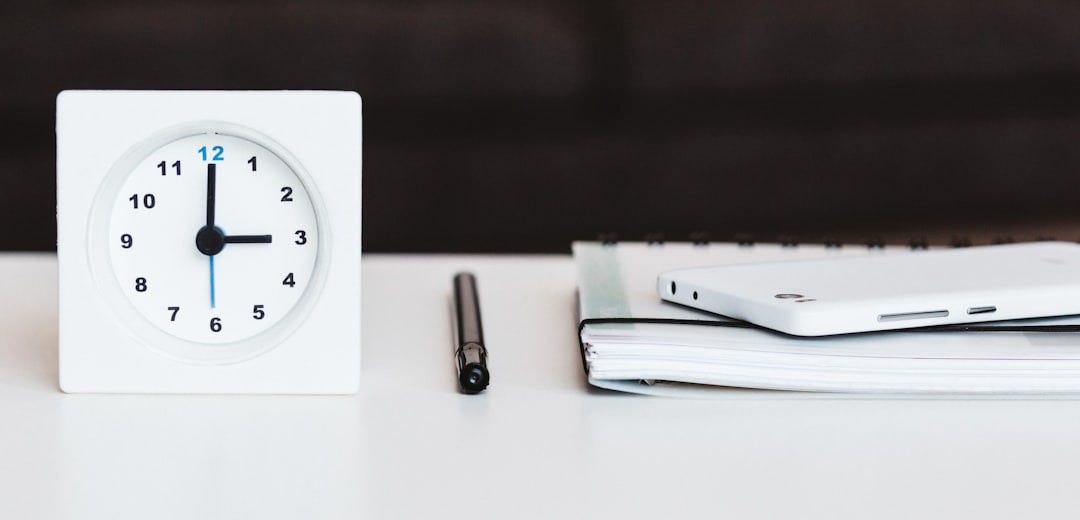 white desk clock near pen and book white desk clock near pen and book