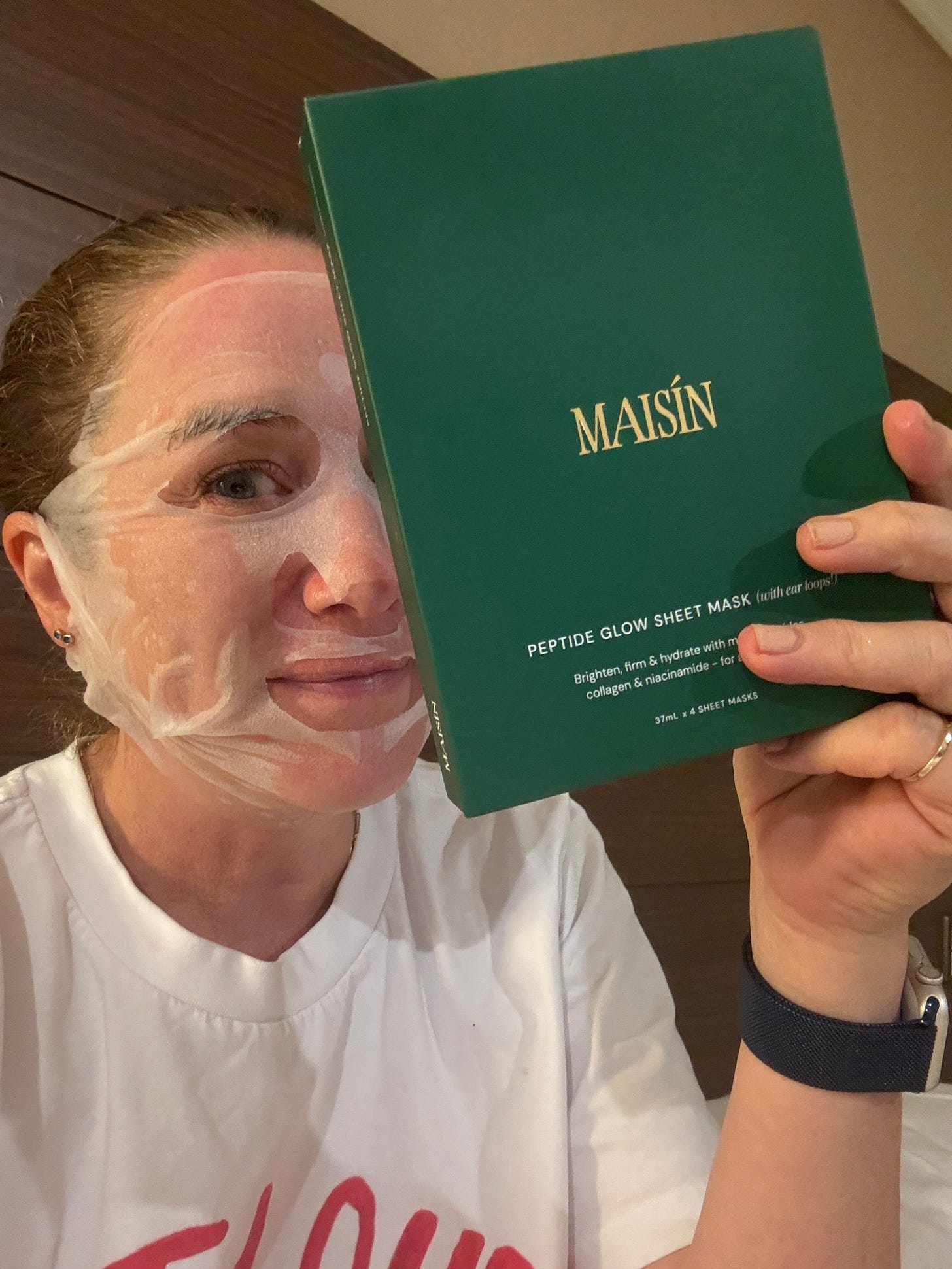 Holly wears Maisin face mask and holds up packaging.