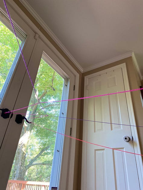Yarn strung up through a house, a child stands in the middle of the yarn