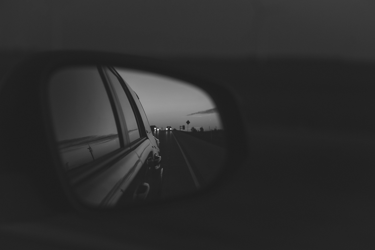 A view of cars in the distance from a car's side view mirror