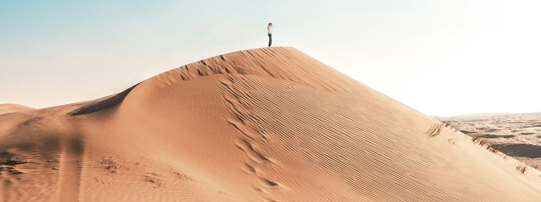 man standing on sand dune man standing on sand dune