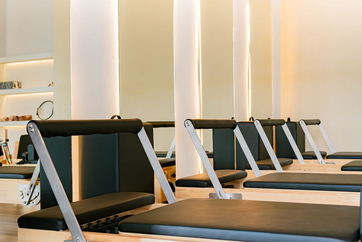 An empty Pilates studio lined with reformer machines.