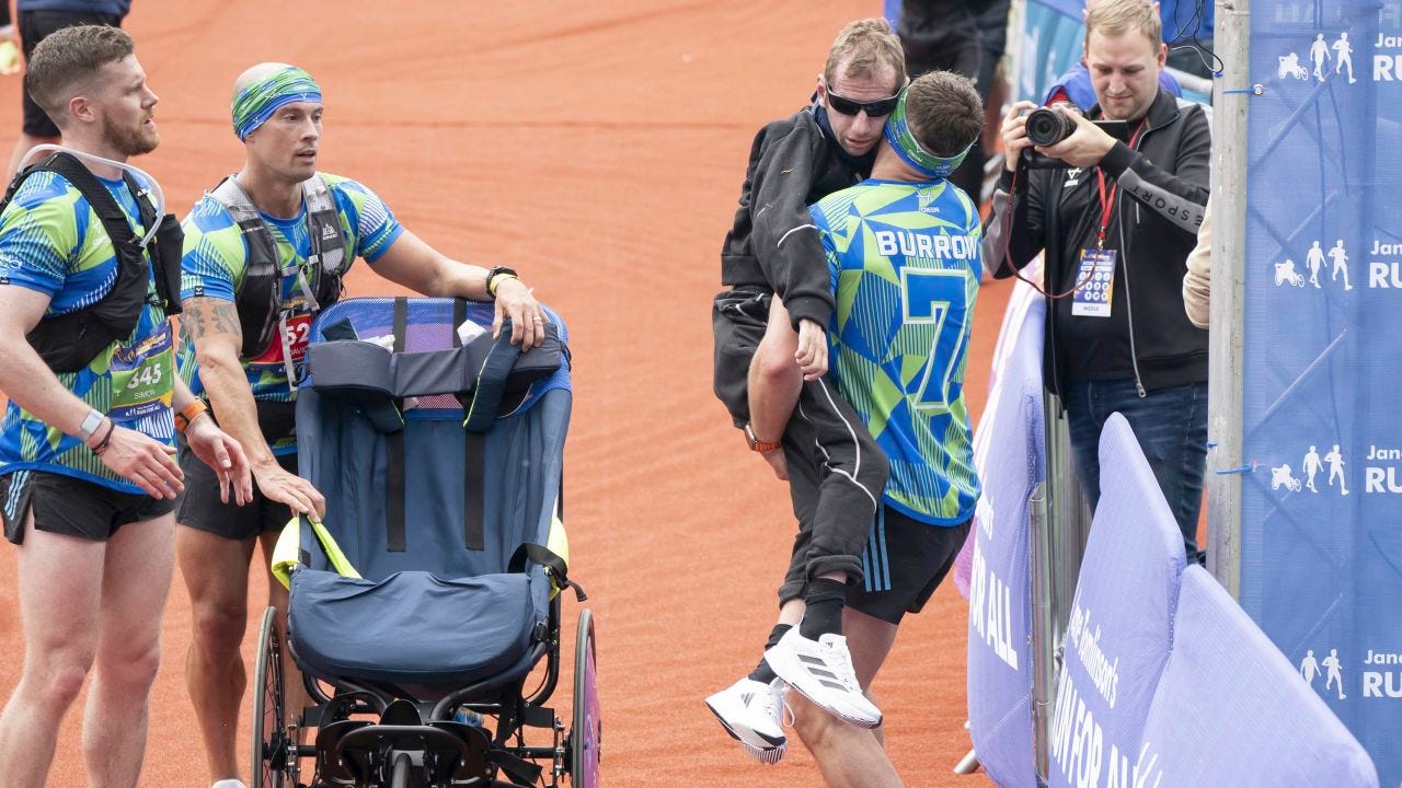 Sinfield carries Burrow across the finish line of the Rob Burrow Leeds Marathon at Headingley Stadium.