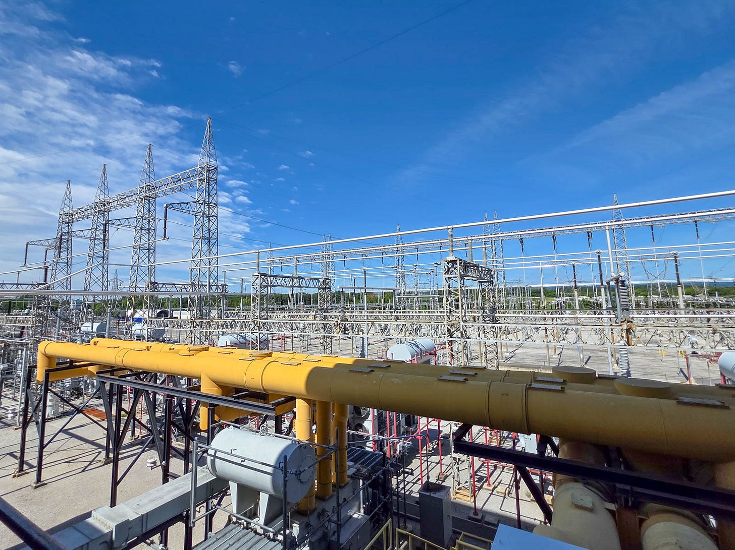 Sequoyah switchyard with steel lattice towers, buswork, and yellow gas-insulated piping under a clear sky. Sequoyah switchyard with steel lattice towers, buswork, and yellow gas-insulated piping under a clear sky.
