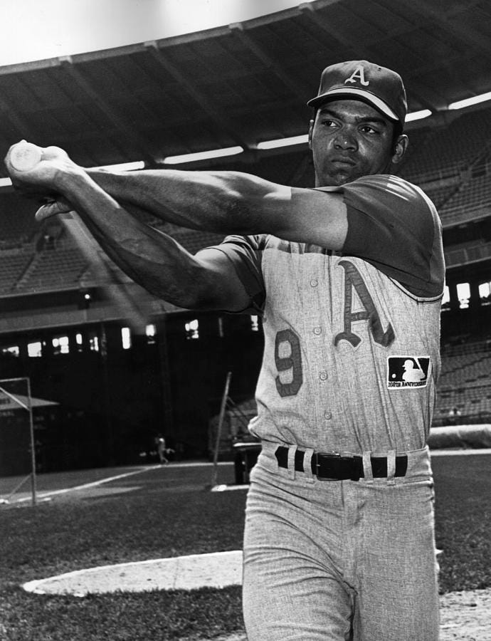 Reggie Jackson swinging a baseball bat on a stadium field