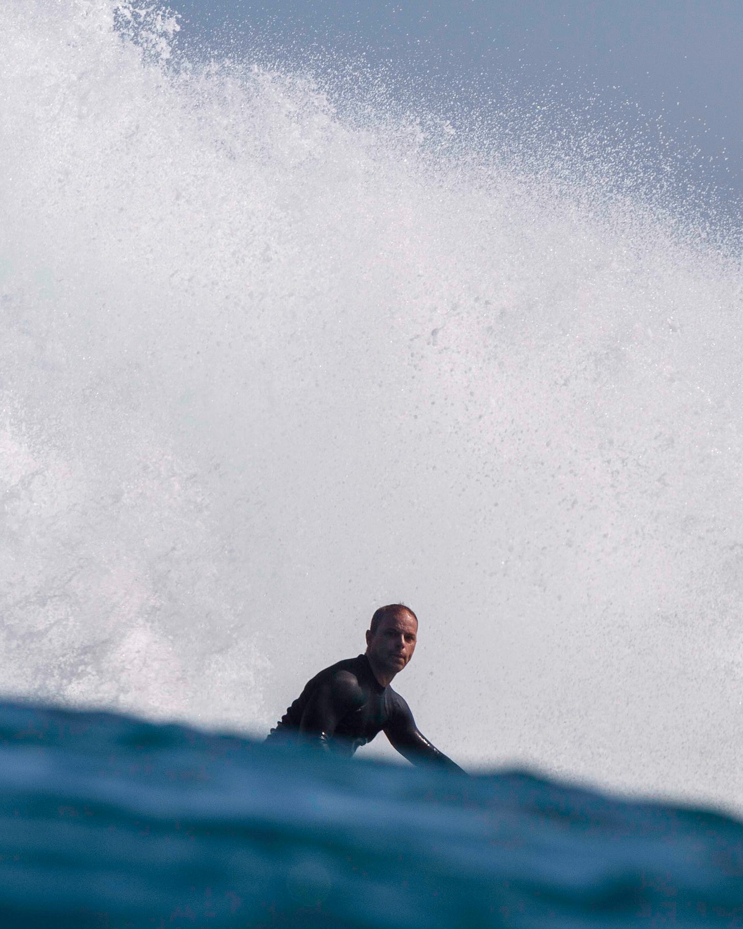 Picture of Nat Sharratt surfing with explosive white water behind him