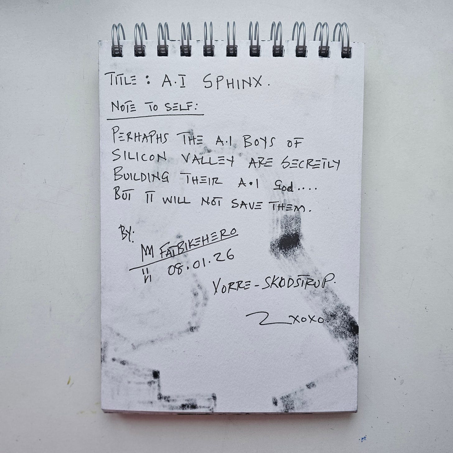 "The back of a sketchbook page with handwritten text in black ink. The text reads: 'Title: A.I SPHINX. Note to Self: Perhaps the A.I boys of Silicon Valley are secretly building their A.I God.... But it will not save them.' The page is signed 'M FatbikeHero', dated '08.01.26', and inscribed 'Vorre - Skødstrup'. There are black ink smudges and bleed-through texture from the front of the artwork." "The back of a sketchbook page with handwritten text in black ink. The text reads: 'Title: A.I SPHINX. Note to Self: Perhaps the A.I boys of Silicon Valley are secretly building their A.I God.... But it will not save them.' The page is signed 'M FatbikeHero', dated '08.01.26', and inscribed 'Vorre - Skødstrup'. There are black ink smudges and bleed-through texture from the front of the artwork."